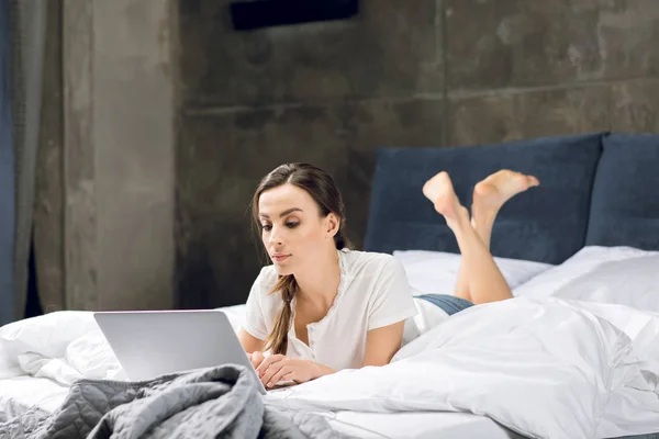 Donna che utilizza il computer portatile a letto — Foto stock