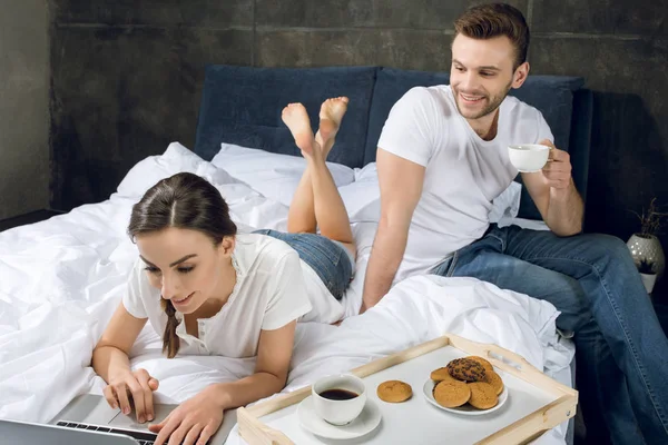 Woman using laptop in bed — Stock Photo