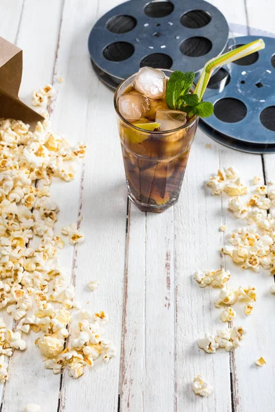 Popcorn with iced tea and film reels — Stock Photo, Image