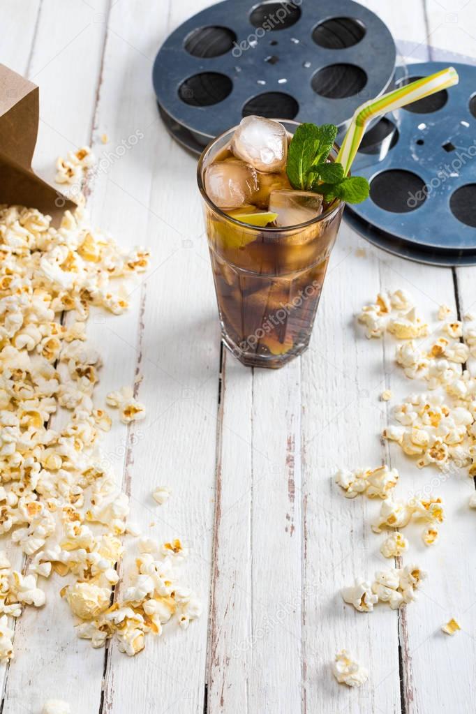 Popcorn with iced tea and film reels  