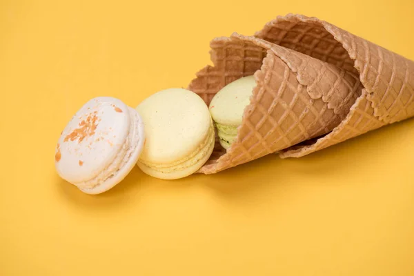 Yellow and white macarons in waffle cones — Stock Photo, Image