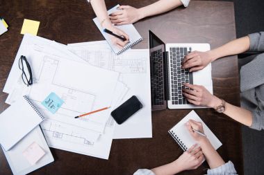 businesswomen writing at notebooks and working on laptop clipart