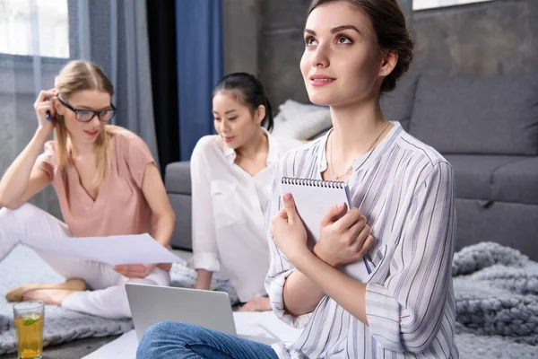 Mujer joven soñando mientras sus colegas trabajan Imagen De Stock