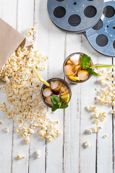 Popcorn with iced tea and film reels — Stock Photo