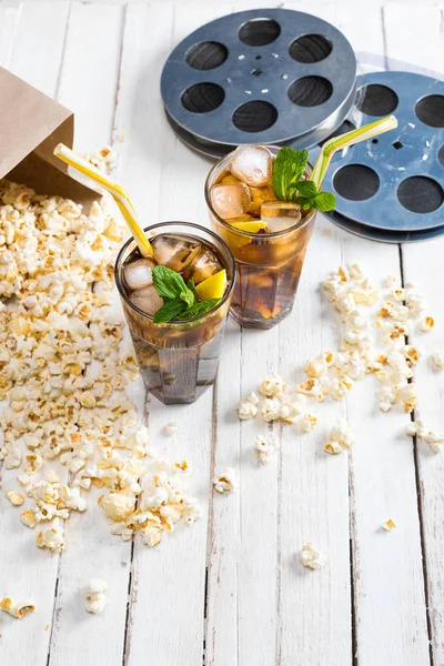 Popcorn with iced tea and film reels — Stock Photo