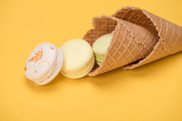 Yellow and white macarons in waffle cones — Stock Photo