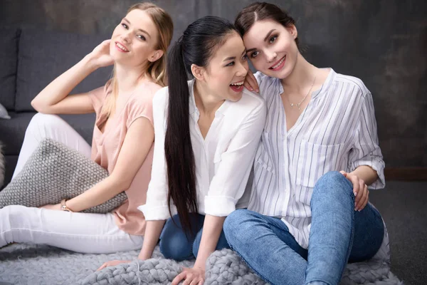 Smiling multiethnic girls sitting on floor — Stock Photo