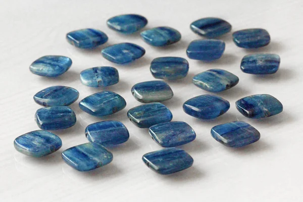 Fotoğraf boncuk doğal taş Kyanit. Doğal mineral mavi kıyanit Beyaz ahşap zemin üzerinde — Stok fotoğraf