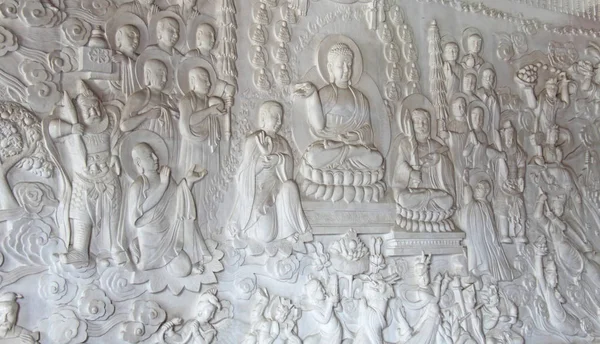 Una imagen de un buda y monjes en una piedra sobre una pared blanca, en el Templo. China. . — Foto de Stock