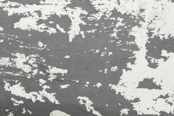 Old flaky paint peeling off a grungy cracked wall. Cracks, scrapes, peeling old paint and plaster on background of old cement wall. An old cement stone wall as vintage cracked. Gray, white background.