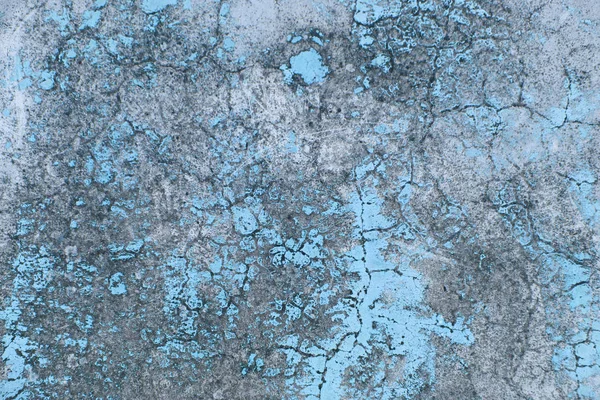 Old flaky paint peeling off grungy cracked wall. Cracks, scrapes, peeling old paint and plaster on background of old cement wall. An old cement stone blue wall vintage cracked. Design with copy space.