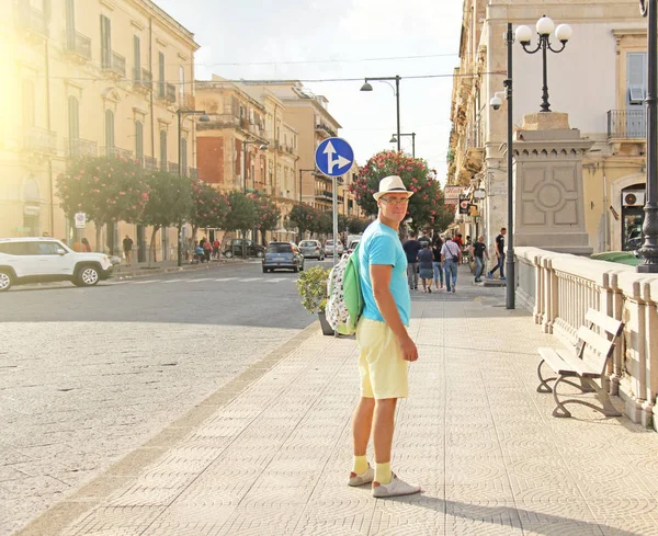 A bald man with a backpack walks through the city of Syracuse. Man is a traveler. The island of Sicily, Italy.