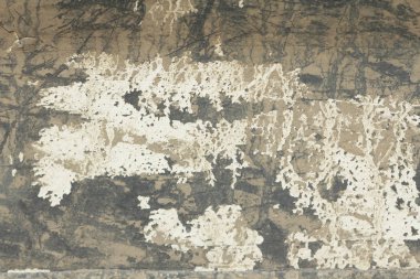 Eski lapa lapa boya soyulmuştu bir Grungy kırık duvar. Eski boya ve sıva eski çimento duvar arka plan üzerinde çatlaklar. Beyaz, gri ve bej noktalar boya. Bir çimento taş duvar eski Vintage kırık olarak.