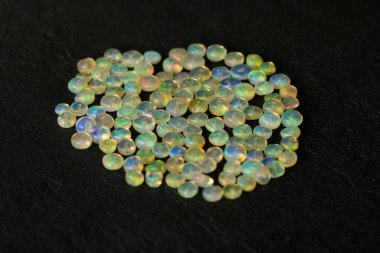 Etiyopya 'dan Opals mücevheri siyah arka planda yatıyor. Gökkuşağı gibi ateşi olan beyaz ateş opalleri. Doğal ateş Etiyopya opalı, mücevher yapmak için küçük taşlar. El yapımı taş mücevherler. Taş yığını.