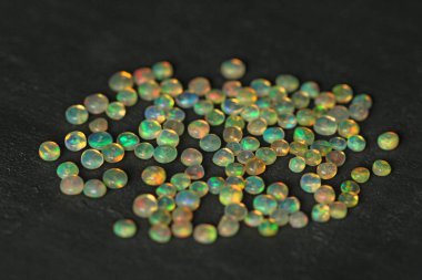 Etiyopya 'dan Opals mücevheri siyah arka planda yatıyor. Gökkuşağı gibi ateşi olan beyaz ateş opalleri. Doğal ateş Etiyopya opalı, mücevher yapmak için küçük taşlar. El yapımı taş mücevherler. Taş yığını.