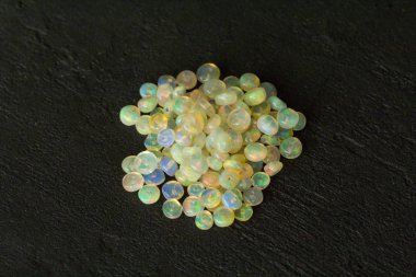 Etiyopya 'dan Opals mücevheri siyah arka planda yatıyor. Gökkuşağı gibi ateşi olan beyaz ateş opalleri. Doğal ateş Etiyopya opalı, mücevher yapmak için küçük taşlar. El yapımı taş mücevherler. Taş yığını.