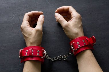 Yetişkin erkek elleri kırmızı erotik deri kelepçeli. Eller esaret altında. Siyah arka planda kırmızı deri kelepçeler. Yetişkin oyunları ve oyuncaklar. BDSM, fetiş aşınma ve yakın plan seks oyuncağı konsepti.