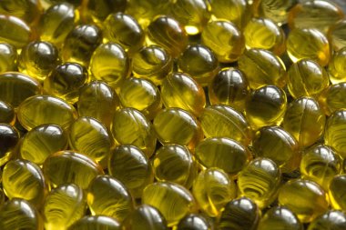 Altın siyah arka plan kapsülleri gıda takviye kapsüllerini kapatın. A vitamini, D3 vitamini, balık yağı, Omega 3, 6, 9, çuha çiçeği yağı, keten tohumu yağı, D vitamini, E vitamini..