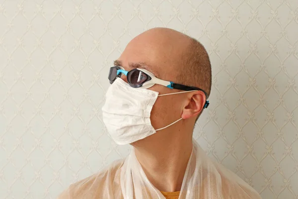 Young Man in medical mask, glasses, protective suit. Man wearing hygienic mask to prevent infection, airborne respiratory illness such as flu, Covid - 2019. Protection against coronavirus, viruses.