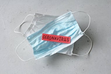 Coronavirus kelimesinin yazıldığı iki tıbbi maske. Kauçuk kulaklıklı cerrahi maske. Tipik 3 katlı cerrahi maske ağız, burun. Prosedür maske bakterisi. Koronavirüse karşı koruma.