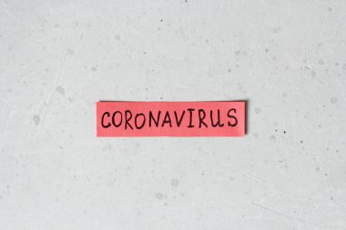 Coronavirus kelimesi açık gri modern arkaplanda, kırmızı bir kağıt parçasına yazılmıştır. Salgın, tehlike, iyileşme.