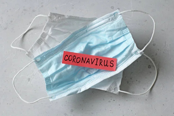 Two Medical mask which word Coronavirus is written. Surgical used mask with rubber ear straps. Typical 3-ply surgical mask cover mouth, nose. Procedure mask bacteria. Protection against coronavirus.