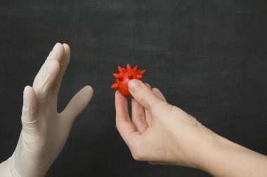 Eldivensiz kırmızı bir koronavirüsü alıp eline almayı reddeden tek kullanımlık plastik bir eldiven verin. Koruyucu tek kullanımlık eldivenler virüslere, koronavirüse ve bakterilere karşı korur..