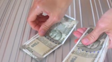 Kadın elleri, açık yeşil Hint Rupisi 'nin açık gri metalik arka planında, Mahatma Gandhi' nin resmine sahip 500 rupilik kağıdını tutuyor, sayıyor ve sayıyor. Yakın plan..