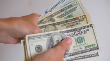 Kadınların elleri sayılıyor, Amerikan dolarlarının farklı değerleri yeniden hesaplanıyor. Yakın plan, bulanık arkaplan.