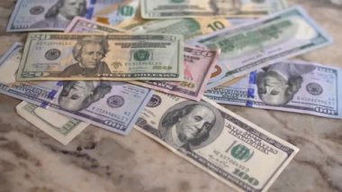 Amerikan parasının farklı değerlerdeki dolarları mermer bir arka planda yatıyor. Yakın plan. Yavaş Hareket.