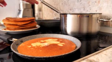 Yeşil silikon spatula kullanan bir kadın eli geleneksel bir Rus krepinin üzerine tereyağı sürer ve ızgarada pişirilir. Tereyağı Rus gözlemesinde erir. Rus gözlemesi pişiriyorum, yakın plan..