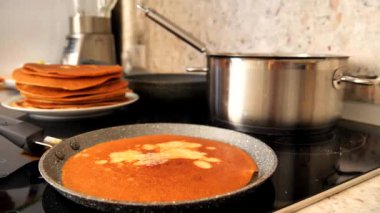 Yeşil silikon spatula kullanan bir kadın eli geleneksel bir Rus krepinin üzerine tereyağı sürer ve ızgarada pişirilir. Tereyağı Rus gözlemesinde erir. Rus gözlemesi pişiriyorum, yakın plan..