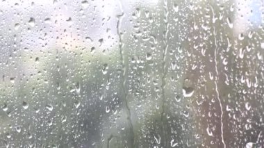 Küçük ve büyük yağmur damlaları ya da su açık saydam bir pencere camından ya da araba camından aşağı akar..