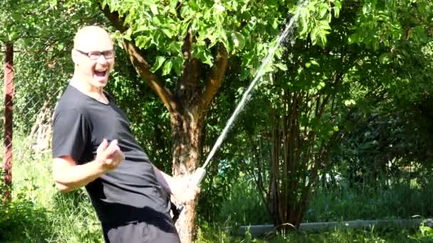 남자는 커다란 물줄기 유우머 즐거움을 정원에 대머리 나무에서 호스에 호스를 — 비디오