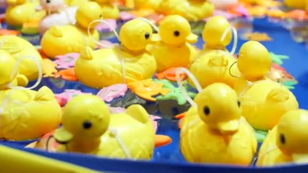 Yellow rubber little duck toys swim in an inflatable pool on a background of blue water. Favorite children's game - catch a duck from the water. Children's amusement park. Hypnosis, dizziness. — Stock Footage Yellow Rubber Little Duck Toys Swim Inflatable Pool Background Blue Royalty Free Stock Footage