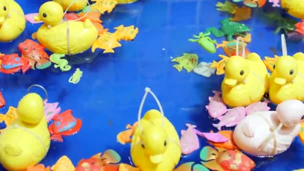 黄色のゴム製の小さなアヒルのおもちゃは 青い水の背景にインフレータブルプールで泳ぐ 好きな子供のゲーム 水からアヒルをキャッチします 子供遊園地 めまい — ストック動画