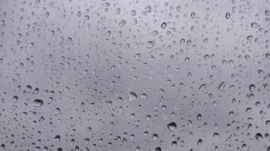 Pencerede yağmur damlaları. Pencereden bir damla yağmur akıyor. Arka planda bulanık binalar olan cam camlarına su damlaları ya da yağmur damlaları. Üzüntü, özlem, donukluk, sonbahar depresyonu, kasvet..