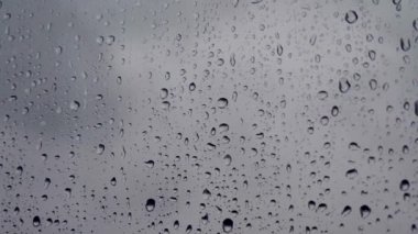 Pencerede yağmur damlaları. Pencereden bir damla yağmur akıyor. Arka planda bulanık binalar olan cam camlarına su damlaları ya da yağmur damlaları. Üzüntü, özlem, donukluk, sonbahar depresyonu, kasvet..