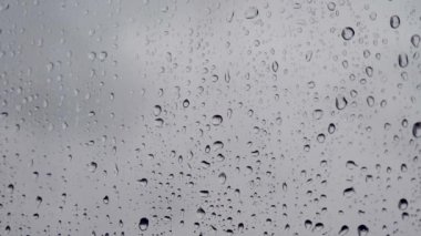 Pencerede yağmur damlaları. Pencereden bir damla yağmur akıyor. Arka planda bulanık binalar olan cam camlarına su damlaları ya da yağmur damlaları. Üzüntü, özlem, donukluk, sonbahar depresyonu, kasvet..