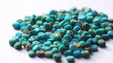 Doğal turkuaz bir taş yığını ya da kaydırak şeklinde yakın plan açık gri bir metal zemin üzerinde dönüyor. Doğal turkuaz taşlar mücevher yaratmak için. Doğal taşlar ve mineraller. Tahsilat taşları.