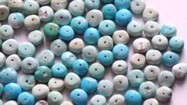 Doğal turkuaz taşı bir yığın ya da kaydırak şeklinde yakın çekim açık gri metal arka planda dönüyor. Doğal turkuaz taşlar mücevher yaratmak için. Doğal taşlar ve mineraller. Tahsilat taşları.