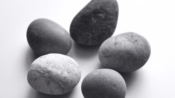 Detailní šedé kulaté kameny se otáčejí na světle šedém pozadí. Obyčejné šedé oblázkové kameny. Pozadí pro meditaci a relaxaci.