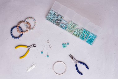 El yapımı mücevherler. Üst Manzara. Boncuklar, mücevher yapmak için aletler. El yapımı için hazırlık. Doğal taşlardan kendi ellerinle mücevher ve bilezikler yarat. Düz yatıyordu. Beyaz arkaplanda.