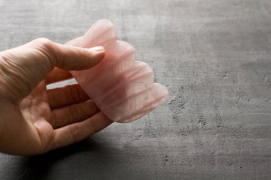 Yüz ve vücut masajı. Dişi el, doğal taş mineral gül kuvarstan yapılmış gouacha 'yı avucunda tutar. Güzellik, yüz ve vücut gençliği için terapi masajı. Metnin için boşluk kopyala.