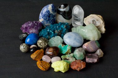 Dünyanın dört bir yanından gelen çok renkli doğal taş ve minerallerin güzel bir koleksiyonu siyah arka planda yatıyor. Amber, Carnelian, Pyrite, ametist, zümrüt, agate. Güzel taşlar ve mineraller