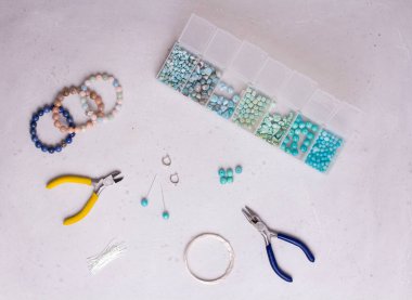 El yapımı mücevherler. Üst Manzara. Boncuklar, mücevher yapmak için aletler. El yapımı için hazırlık. Doğal taşlardan kendi ellerinle mücevher ve bilezikler yarat. Düz yatıyordu. Beyaz arkaplanda.