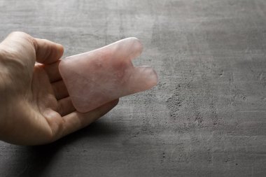 Yüz ve vücut masajı. Dişi el, doğal taş mineral gül kuvarstan yapılmış gouacha 'yı avucunda tutar. Güzellik, yüz ve vücut gençliği için terapi masajı. Metnin için boşluk kopyala.