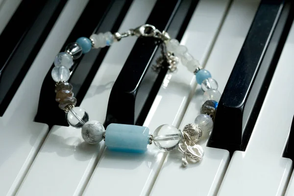 Auf Schwarzen Und Weißen Klaviertasten Liegt Ein Handgefertigtes Blaues Armband — Stockfoto