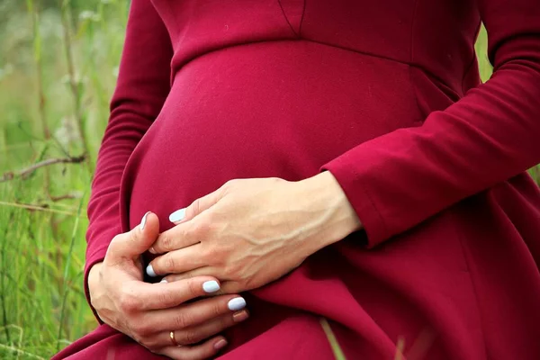 Femme enceinte en robe rouge tenant son ventre — Photo