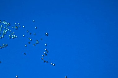 Mavi arka planda bir sürü gümüş küçük top var. Soyut 